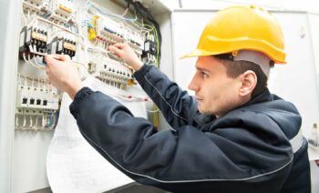 One electrician builder at work with assembly drawing inspecting high voltage power electric line distribution fuseboard